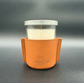 Candle in a glass holder with a brown leather sleeve on a gray background