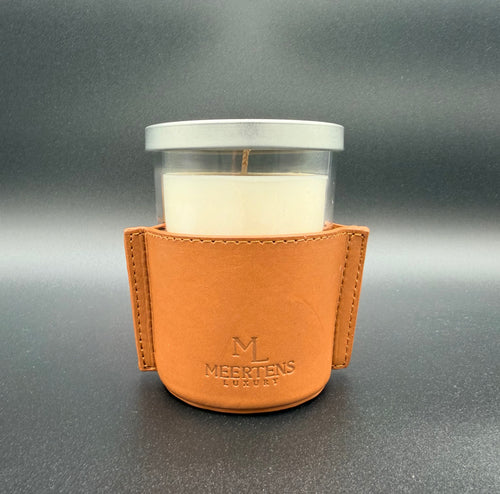 Candle in a glass holder with a brown leather sleeve on a gray background