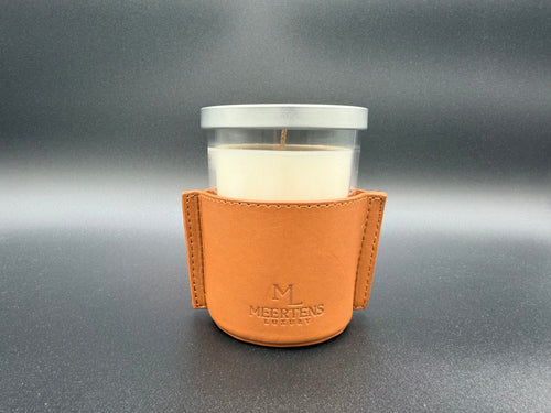 Candle in a glass holder with a leather sleeve on a gray background