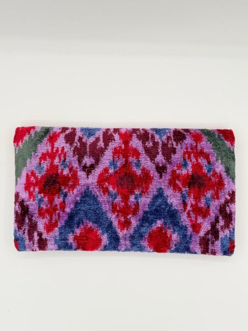 A rectangular woven textile with a bold geometric pattern in red, purple, blue, and green, displayed flat against a plain white background.