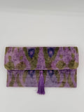 A folded purple and olive green patterned textile item with a matching purple tassel, photographed against a plain light background.
