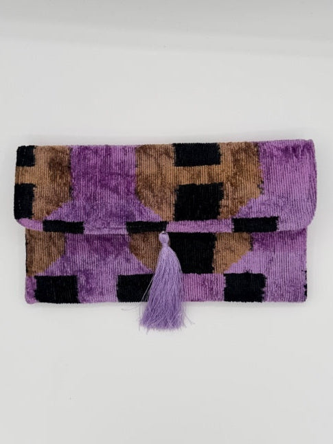 A folded purple woven textile with a geometric pattern in purple, black, and brown, featuring a matching purple tassel tie, shown on a plain white background.