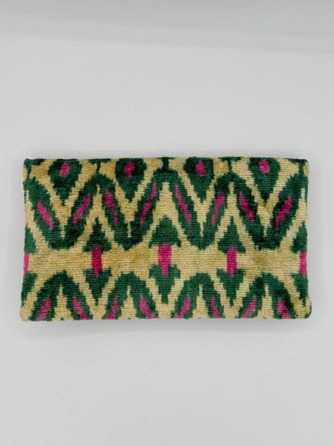 A rectangular woven textile with a geometric ikat pattern in green, beige, and pink, displayed flat against a light gray background.