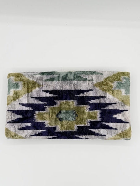 A rectangular woven textile with an abstract geometric pattern in navy blue, olive green, and cream, shown hanging against a plain white wall.